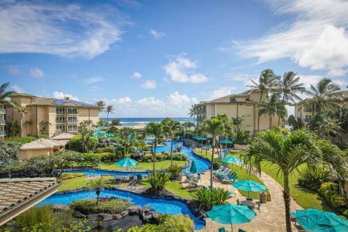 eine Luftansicht eines Resorts mit Pools und Sonnenschirmen in der Unterkunft Waipouli Beach Resort and Spa Kauai by OUTRIGGER in Kapaa