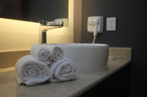- une pile de serviettes sur un comptoir dans la salle de bains dans l'établissement Hotel veinti 3 Tapachula, à Raymundo Enríquez