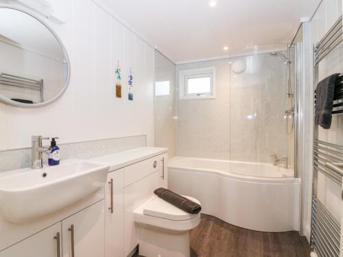 a white bathroom with a sink and a toilet and a tub at Eden Fields Lodge in Cupar