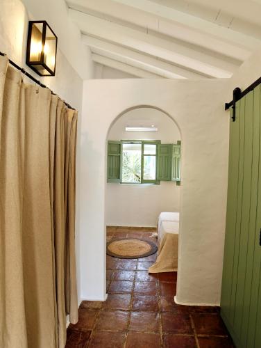 a hallway with a bed and a green door at Alojamiento rural CASAPIÑA in Conil de la Frontera