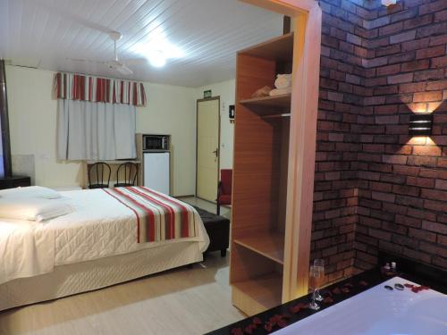 a bedroom with a bed and a brick wall at Cabanas Brisa dos Canyons in Cambará