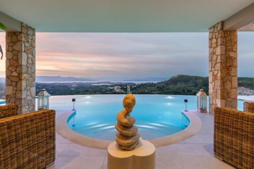 a resort pool with a stack of stones in the middle at Villa Nirvana in Áyioi Dhéka