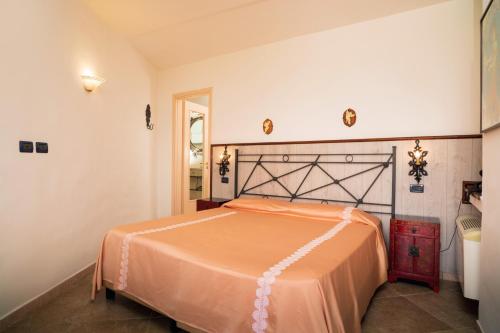 ein Schlafzimmer mit einem Bett mit einer orangefarbenen Tagesdecke in der Unterkunft Garden Cottage I Dammusi - Limoni in Castelmola