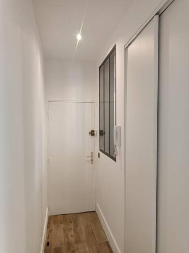 un couloir blanc avec une porte en verre et un miroir dans l'établissement Le Victor , à Saint-Raphaël