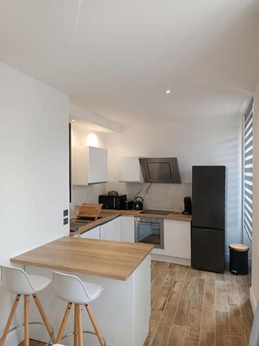 Il comprend une cuisine équipée d'un réfrigérateur noir et de placards blancs. dans l'établissement Le Victor , à Saint-Raphaël