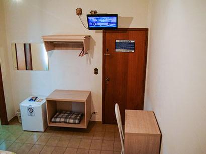 a room with a room with a table and a television at Hotel Nações in Presidente Prudente