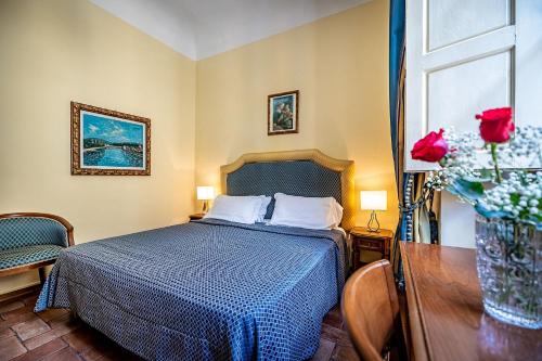 a bedroom with a bed and a vase of roses at Soggiorno Campos in Florence
