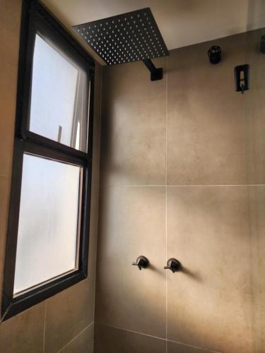 baño con ducha con 2 grifos y ventana en Apartamento completo, en Río de Janeiro