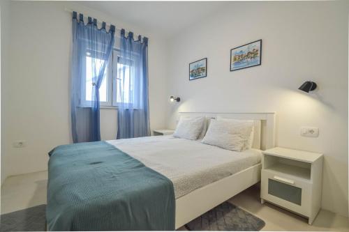 a white bedroom with a bed and a window at Apartment Kaplja in Novigrad Istria