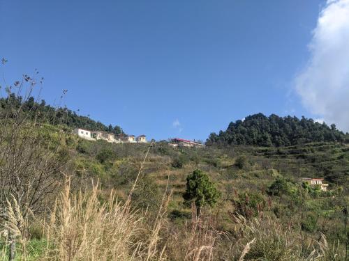 a hill with houses on top of it at NamaStay Himalayas, KANATAL in Kanatal