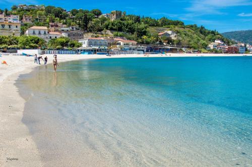 a beach with people walking on the sand and the water at Il Nocchiero City Hotel in Soverato Marina