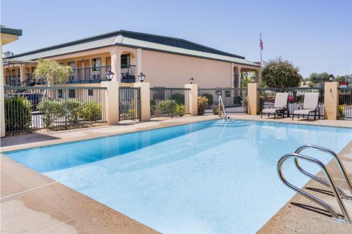 einen Pool mit Stühlen und ein Gebäude in der Unterkunft Days Inn by Wyndham Macon I-475 in Macon