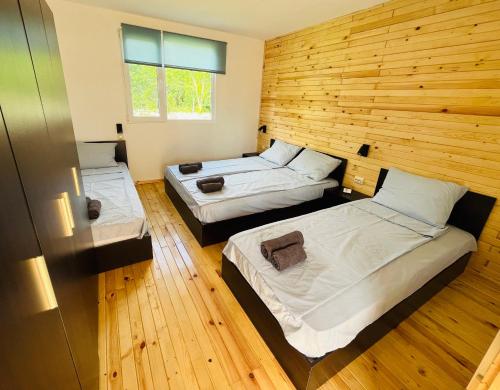 a room with two beds and a wooden wall at CozyHut Бунгало под Наем in Chernomorets