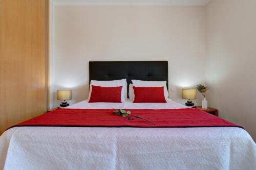 a bedroom with a large bed with red pillows at Rooftop pool, 200m from sea, city center in Olhão