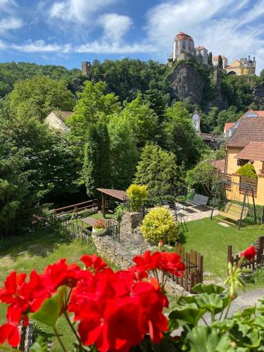 a garden with red flowers and a castle on a hill at Pension Hamry in Vranov nad Dyjí