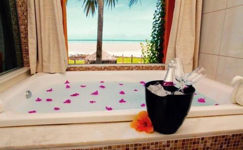 bañera con una botella de champán y flores en Enseada dos Mares Beach Bungalows en São Miguel do Gostoso