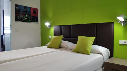 a bedroom with a large white bed with green walls at Huéspedes Sa Font in Ibiza Town