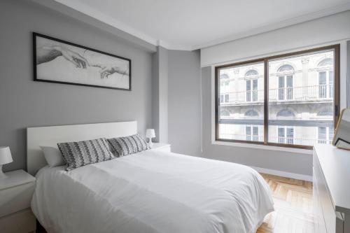 a white bedroom with a bed and a window at Oporto 4 in Vigo