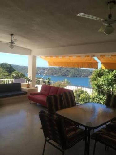 a living room with a red couch and a balcony at Hermosa Casa Lomas del Marques Diamante in Acapulco