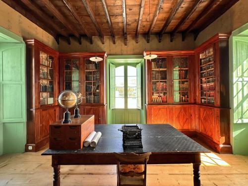 Zimmer mit einem Tisch, einem Fenster und Bücherregalen in der Unterkunft Hotel Emblemático La Casa de los Naranjos in Haría