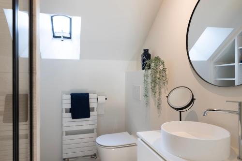 een witte badkamer met een wastafel en een spiegel bij Huys17 in Hasselt