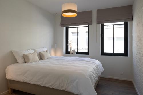 een slaapkamer met een groot wit bed en 2 ramen bij Huys17 in Hasselt