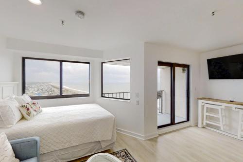 a white bedroom with a bed and two windows at Renaissance 1009 in Myrtle Beach