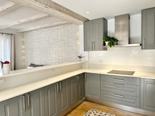 a kitchen with gray cabinets and a brick wall at Old Town Modern Flat, 4 Minutes From Beach - EaW Homes in Marbella