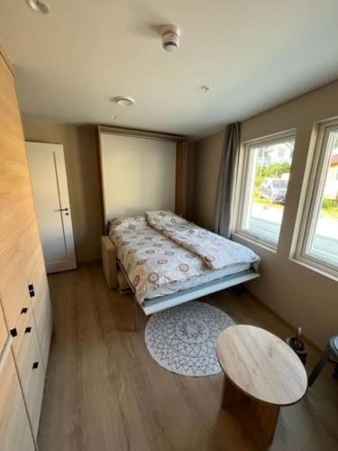 a bedroom with a bed and a table and two windows at Studio Leiligheit in Sogndal