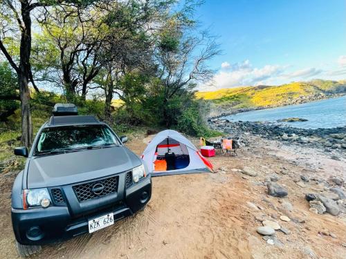 un'auto parcheggiata accanto a una tenda su una spiaggia di Epic Maui Car Camping a Kahului