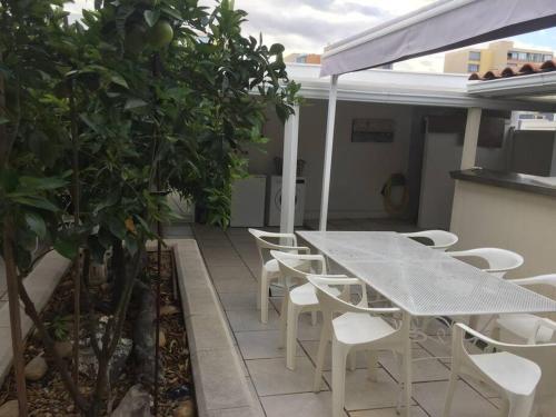 une table et des chaises sur un balcon avec un arbre dans l'établissement Villa plein pied, 2 eme ligne plage sable fin, à Mauguio