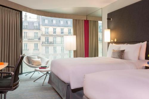 パリにあるルネッサンス パリ アルク ドゥ トリオンフ ホテルのベッド2台と大きな窓が備わるホテルルームです。