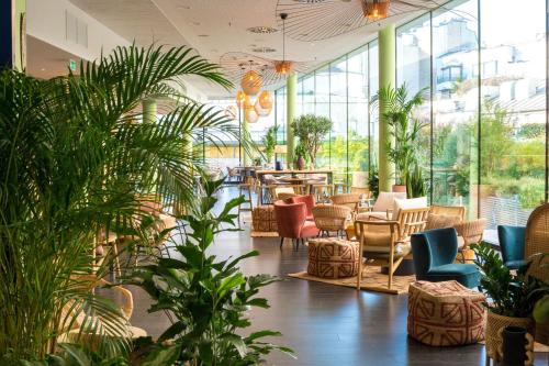 un hall avec des chaises et des plantes dans un bâtiment dans l'établissement Renaissance Paris Arc de Triomphe Hotel, à Paris
