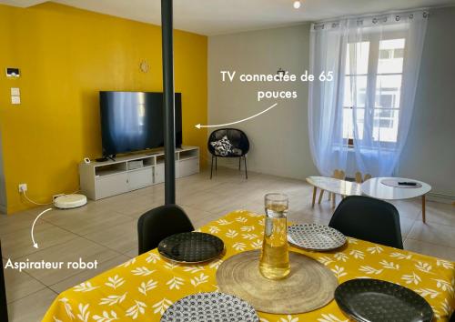 un salon avec une table et une télévision dans l'établissement Le petit jardinet de Tarare, à Tarare