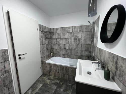 een badkamer met een wastafel, een bad en een spiegel bij Boutique apartments 1 in Sînpetru