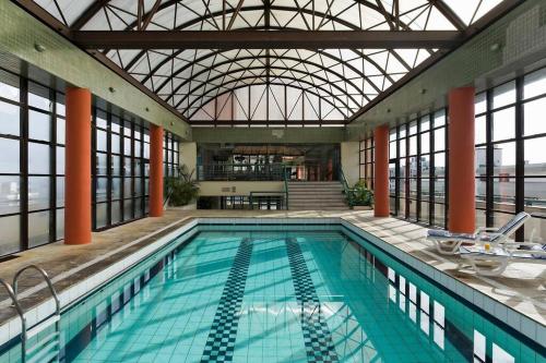 an indoor swimming pool with a glass ceiling at Flat Avenida Independência in Porto Alegre