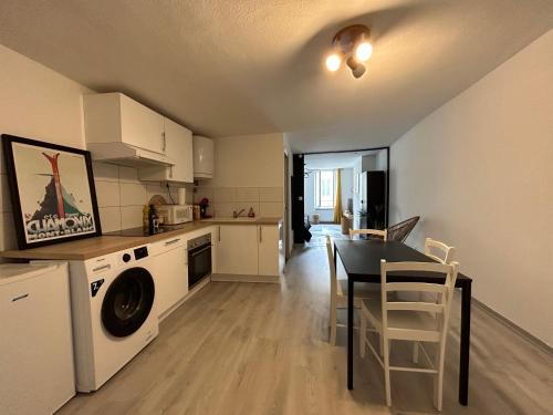 une cuisine et une salle à manger avec une table et un lave-linge dans l'établissement Le Poincaré, à 1 min de la gare, à Nancy