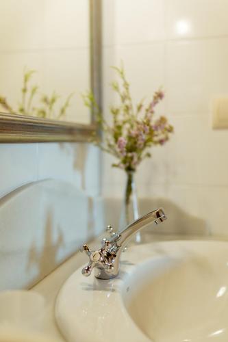 a bathroom sink with a faucet and a vase of flowers at El Molino de Bonaco in San Vicente de la Barquera