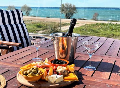 a table with a plate of food and a bottle of wine at Villa Arkadia Seafront Villa Ai-Lagoudis Beach in Kyparissia