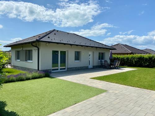 a house with a pitched roof and a lawn at Babóca Apartman - Siófok-Sóstó in Siófok