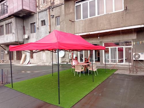 a red umbrella over a table with chairs on grass at Sun city hostel in Yerevan
