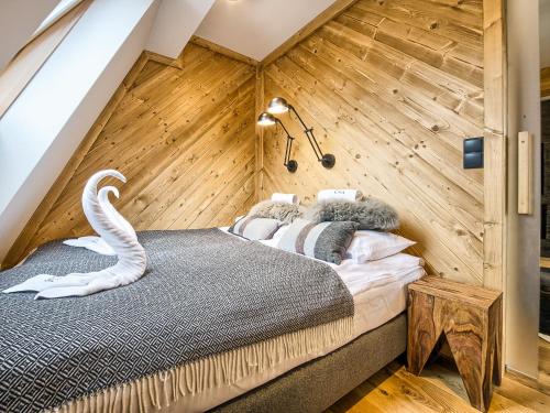 a bed in a room with a wooden wall at VisitZakopane - Tatra Ski Apartment in Zakopane
