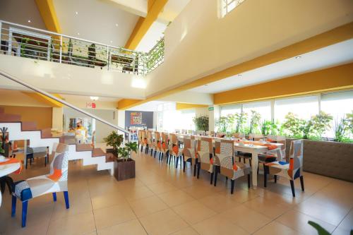 un comedor con mesas, sillas y ventanas en TRYP by Wyndham Chetumal, en Chetumal