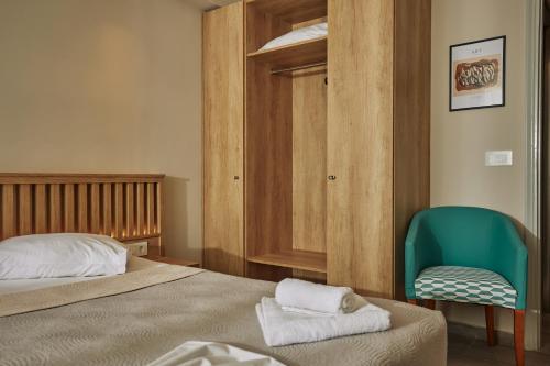 a bedroom with a bed and a green chair at Iniohos Zante Hotel & Suites in Argasi