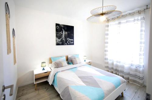 a white bedroom with a bed and a chandelier at L'instant T 4* Balnéo, Sauna et Parking Privé in Colmar