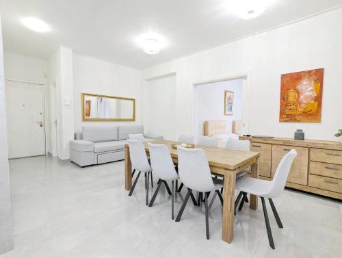 een eetkamer met een houten tafel en witte stoelen bij Victroria Grand Palace Apartment in Athene