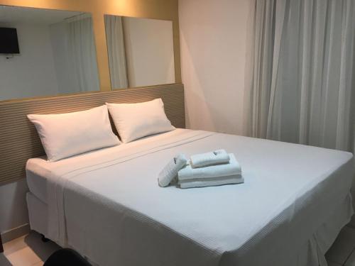 a bed with two towels sitting on top of it at Hotel Pousada Kairos Manaira in João Pessoa