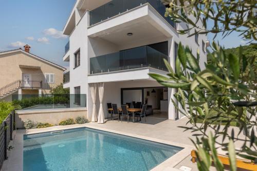 a house with a swimming pool in front of it at Luxury apartment Marco Polo with a private swimming pool with salt sea water in Punat