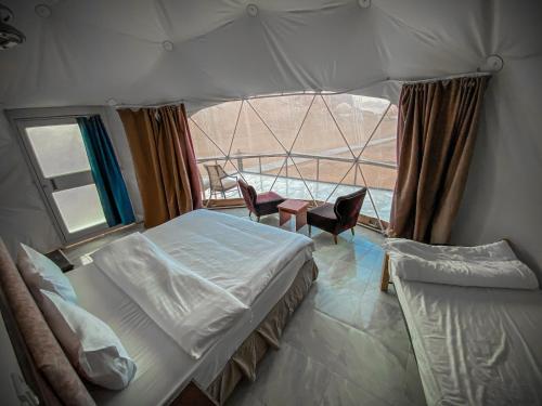 a bedroom with a bed and a window with chairs at Tower Rum Camb in Wadi Rum
