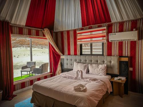 a bedroom with a bed with red curtains and a window at Tower Rum Camb in Wadi Rum